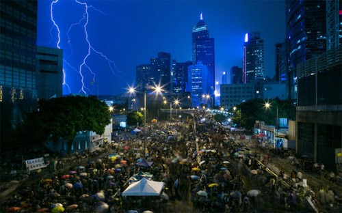 Thời tiết ở Hồng Kông hôm qua nóng nực vào ban ngày, có sớm chớp và mưa vào buổi tối, nhưng người biểu tình không hề nao núng - Ảnh: Bloomberg.<br>