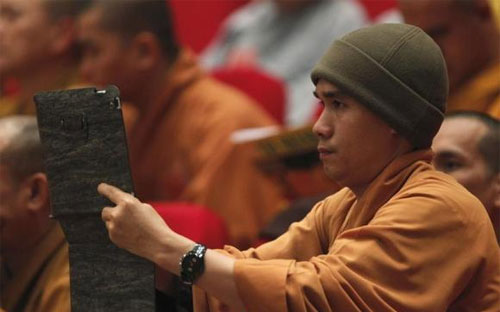 Một nhà sư Việt Nam đang dùng iPad chụp ảnh - Ảnh: Reuters.<br>