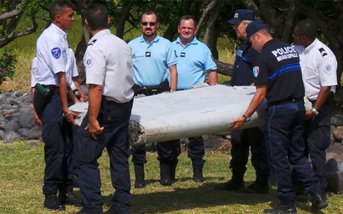 Các nhà chức trách và mảnh vỡ được tìm thấy trên đảo Reunion hồi tháng 7. Mảnh vỡ này đã được Pháp xác nhận là của chuyến bay mất tích MH370 - Ảnh: Reuters.<br>