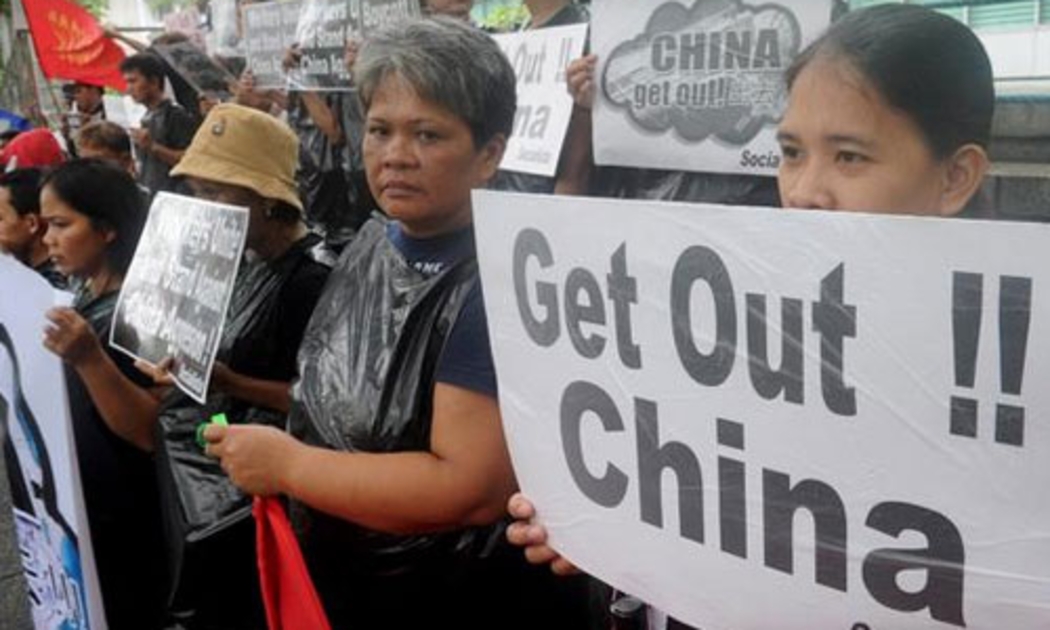 Người dân Philippines tập trung trước lãnh sự quán Trung Quốc ở quận tài chính ở Manila để bày tỏ sự phản đối Bắc Kinh trong vấn đề biển Đông ngày 10/7 - Ảnh: Getty/CBS.<br>