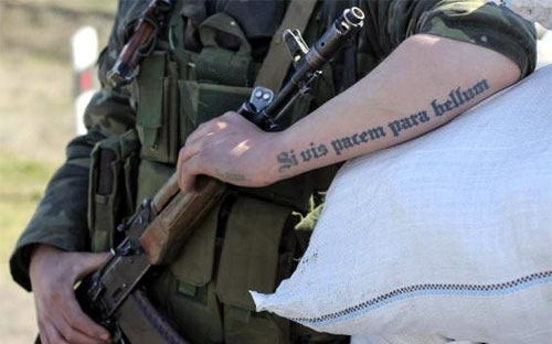 Một người lính Ukraine tại chốt gác ở Salkovo, gần Crimea, với dòng chữ xăm trên tay có nghĩa: "Nếu muốn hòa bình, phải chuẩn bị cho chiến tranh" - Ảnh: Reuters.<br>