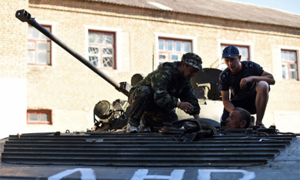 Các phần tử nổi dậy Ukraine đang sửa một xe tăng do quân chính phủ bỏ lại ở Komsomolske, gần Donetsk - Ảnh: AFP/Getty/Bloomberg.<br>