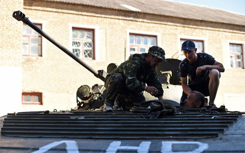 Các phần tử nổi dậy Ukraine đang sửa một xe tăng do quân chính phủ bỏ lại ở Komsomolske, gần Donetsk - Ảnh: AFP/Getty/Bloomberg.<br>