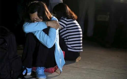 Thân nhân hành khách tàu Ngôi sao phương Đông ngày 4/6 ngồi đợi tin bên bờ sông Dương Tử nơi con tàu bị chìm hôm 1/6 - Ảnh: Reuters.<br>