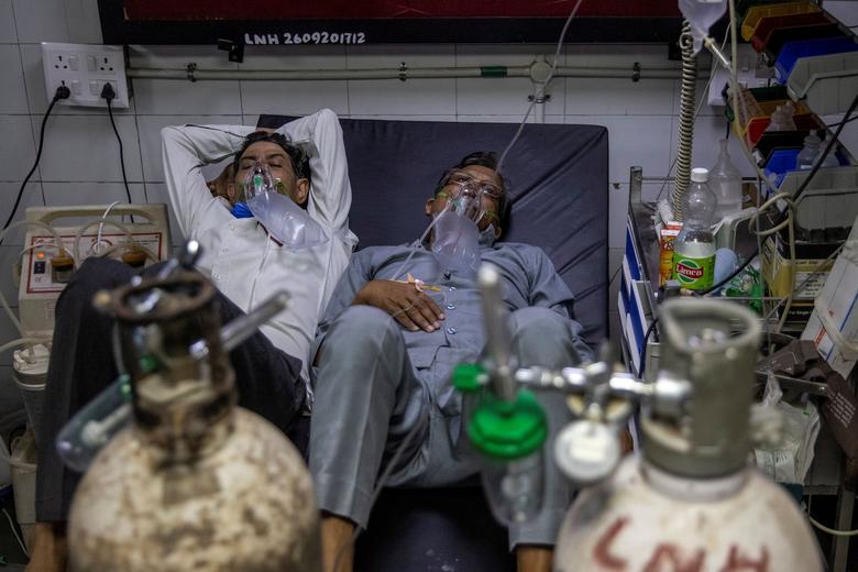 Hai bệnh nhân Covid nằm chung giường trong một bệnh viện ở New Delhi - Ảnh: Reuters.