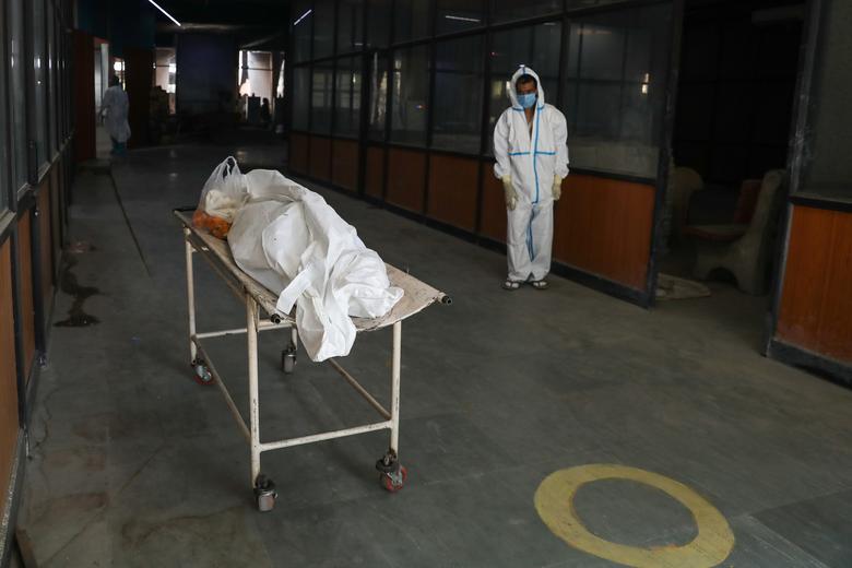 Người thân bất lực đứng nhìn thi thể một bệnh nhân tử vong vì Covid - Ảnh: Reuters.