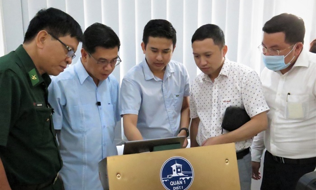 Ông Nguyễn Văn Dũng (thứ hai, từ trái sang) cùng các đại biểu trải nghiệm hệ thống định danh khách hàng điện tử tại UBND Quận 1.