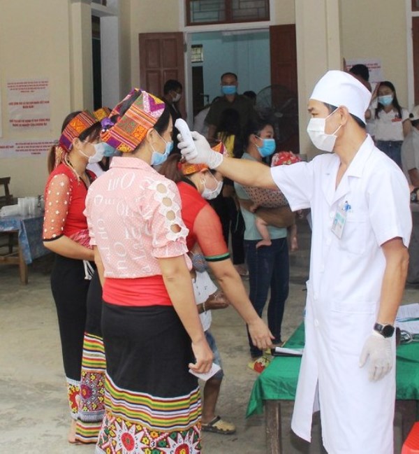 Cán bộ y tế kiểm tra thân nhiệt của cử tri tại điểm bỏ phiếu ở xã Thạch Ngàn, huyện Con Cuông, Nghệ An - Ảnh: CTV.