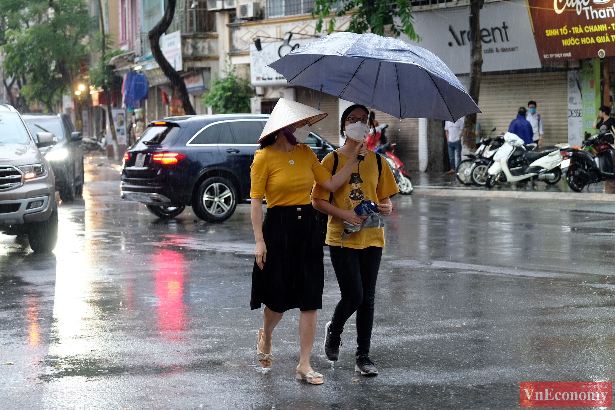 Nhiều phụ huynh che ô đưa con vào điểm thi. Mặc dù được động viên quay về nhà để tránh tụ tập đông người, nhiều phụ huynh vẫn lo lắng mà nán lại đợi tin con.