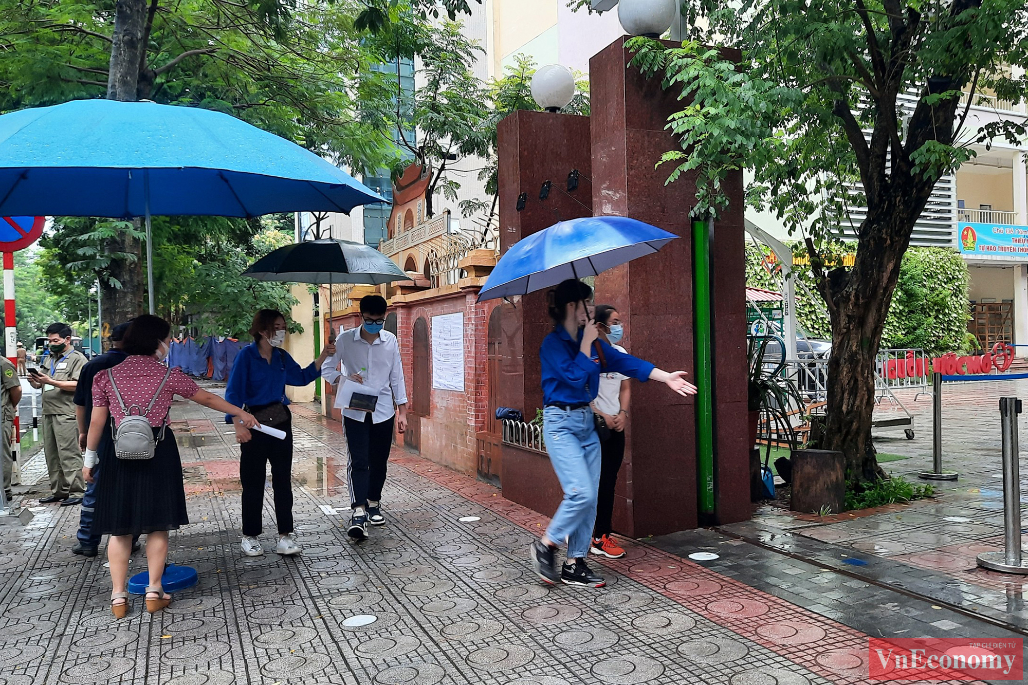 Để tránh tập trung đông người, người đưa, đón thí sinh phải dừng cách điểm thi 50 mét. Thí sinh được lực lượng thanh niên tình nguyện che ô đưa vào điểm thi.