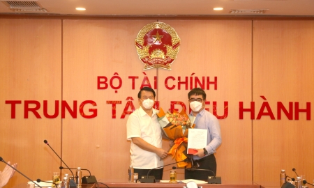 Thứ trưởng Bộ Tài chính Nguyễn Đức Chi (bên trái) trao quyết định và tặng hoa chúc mừng ông Ngô Việt Trung.