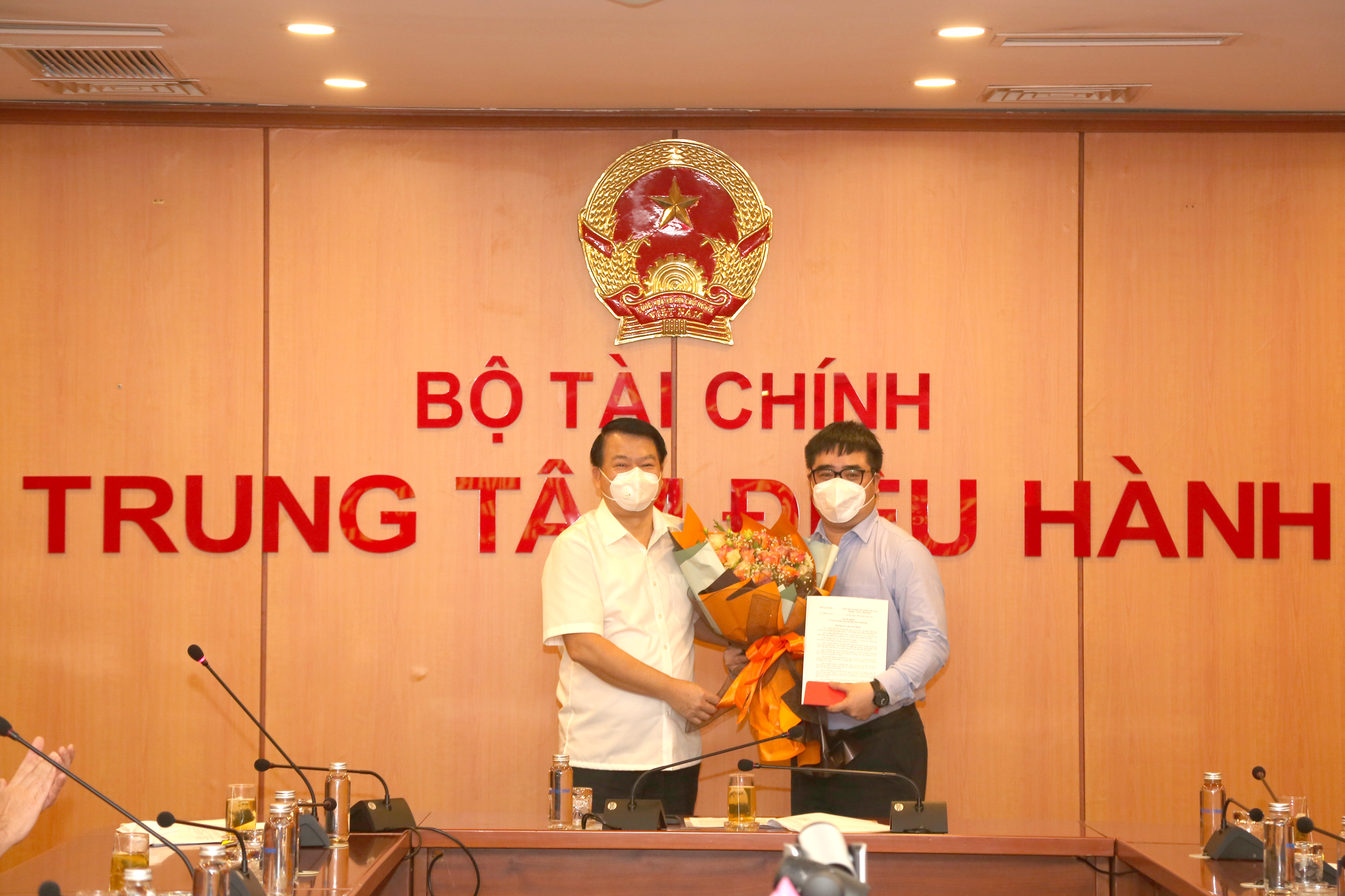 Thứ trưởng Bộ Tài chính Nguyễn Đức Chi (bên trái) trao quyết định và tặng hoa chúc mừng ông Ngô Việt Trung.