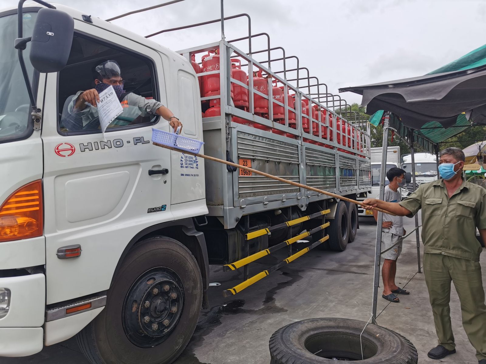 Các phương tiện vận chuyển hàng thiết yếu trình giấy tờ để kiểm soát  tại bãi tập kết hàng hóa, trạm thu phí T2, quận Cái Răng. Ảnh: Báo Cần Thơ