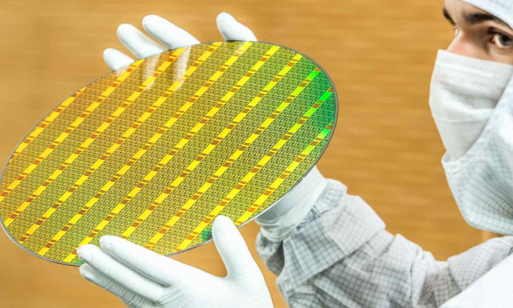 Một nhân viên của GlobalFoundries cầm một tấm bán dẫn 300 mm tại nhà máy sản xuất chip của công ty ở Dresden, Đức vào ngày 1/7 - Ảnh: AP
