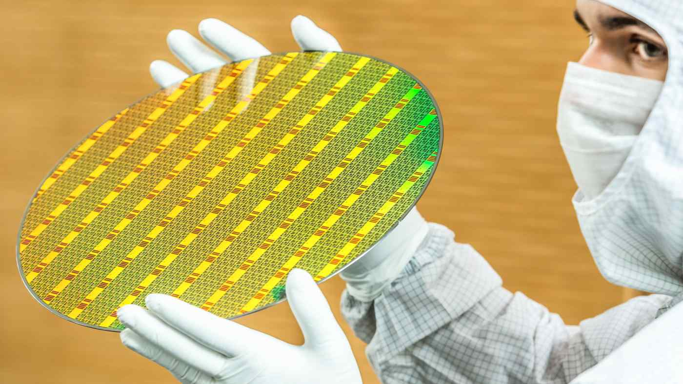 Một nhân viên của GlobalFoundries cầm một tấm bán dẫn 300 mm tại nhà máy sản xuất chip của công ty ở Dresden, Đức vào ngày 1/7 - Ảnh: AP