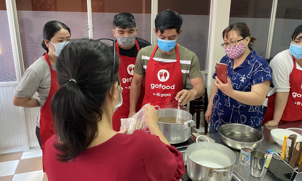 Tài xế Ngô Công Hưởng (áo xanh lá) thực hành nấu trân châu cho món trà sữa.