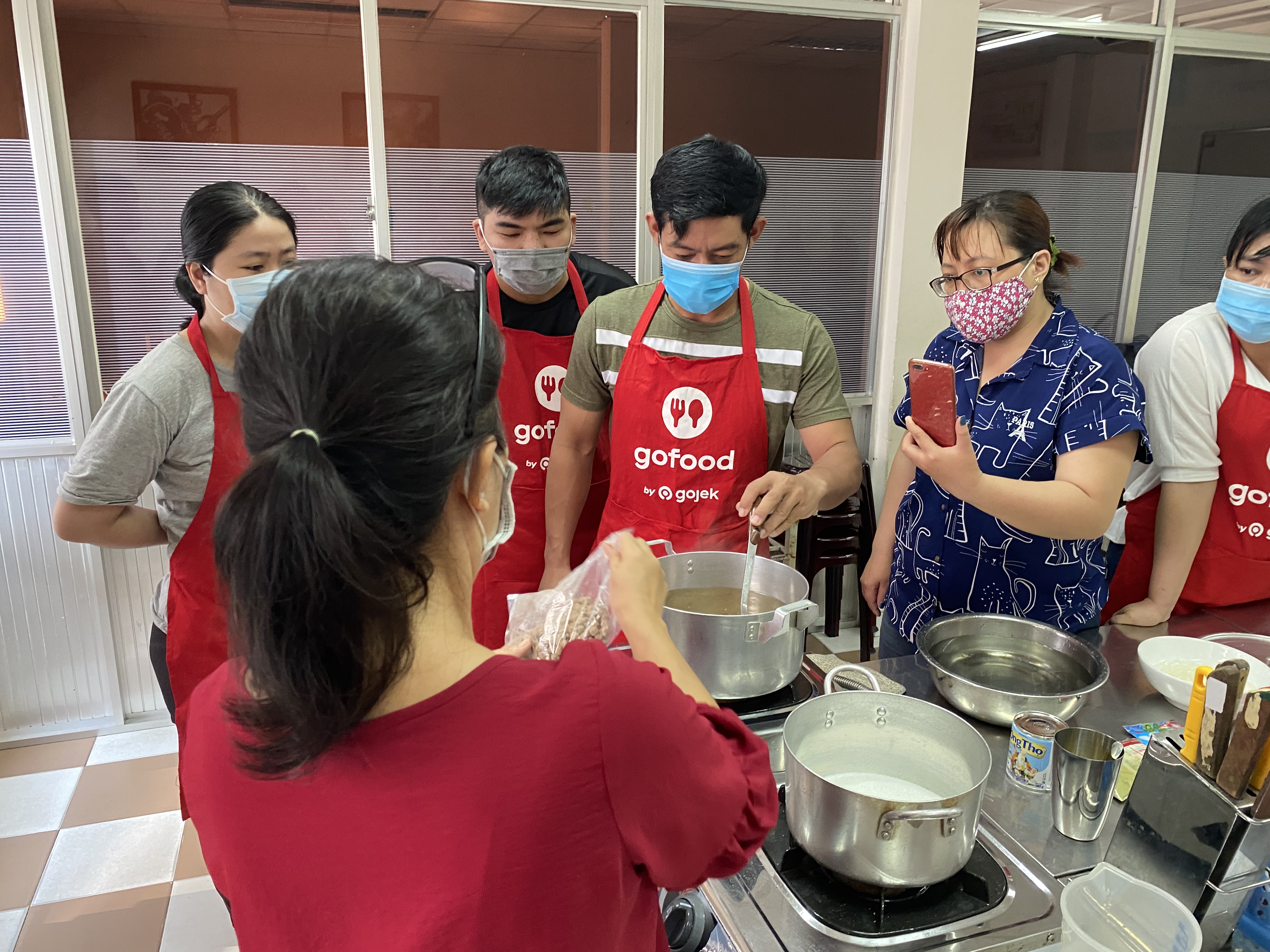 Tài xế Ngô Công Hưởng (áo xanh lá) thực hành nấu trân châu cho món trà sữa.