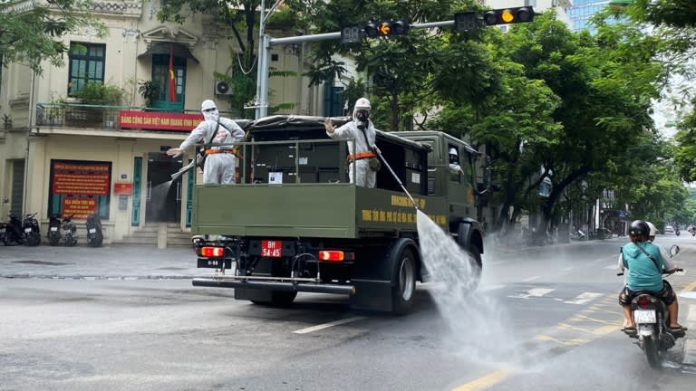 Phun khử trùng đường phố khi Hà Nội áp dụng phong tỏa trong đợt bùng phát dịch Covid-19 vào tháng 7 - Ảnh: Reuters