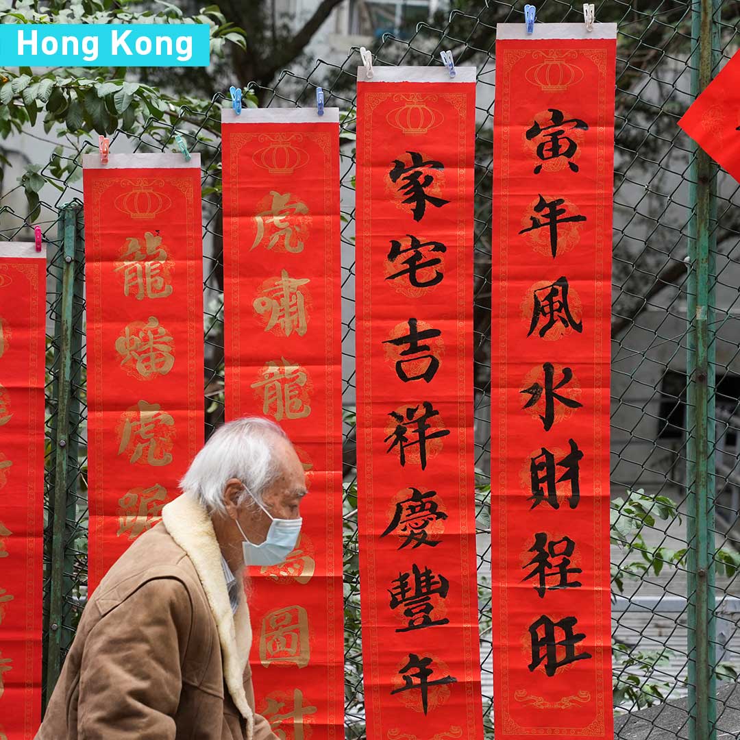 Một cụ gi&agrave; đi qua c&aacute;c tấm biển treo c&acirc;u đối mừng năm mới Nh&acirc;m Dần tại Hồng K&ocirc;ng, Trung Quốc - Ảnh: CGTN