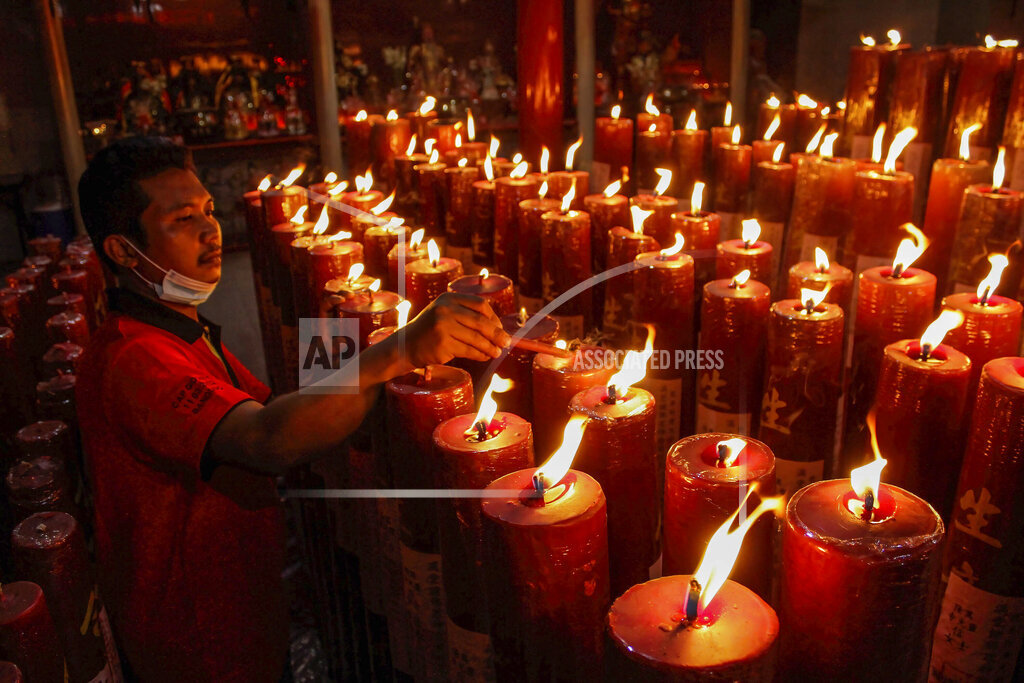 Một người đ&agrave;n &ocirc;ng thắp nến tại Đền Dharma Ramsi, Bandung, Indonesia trong đ&ecirc;m giao thừa - Ảnh: AP