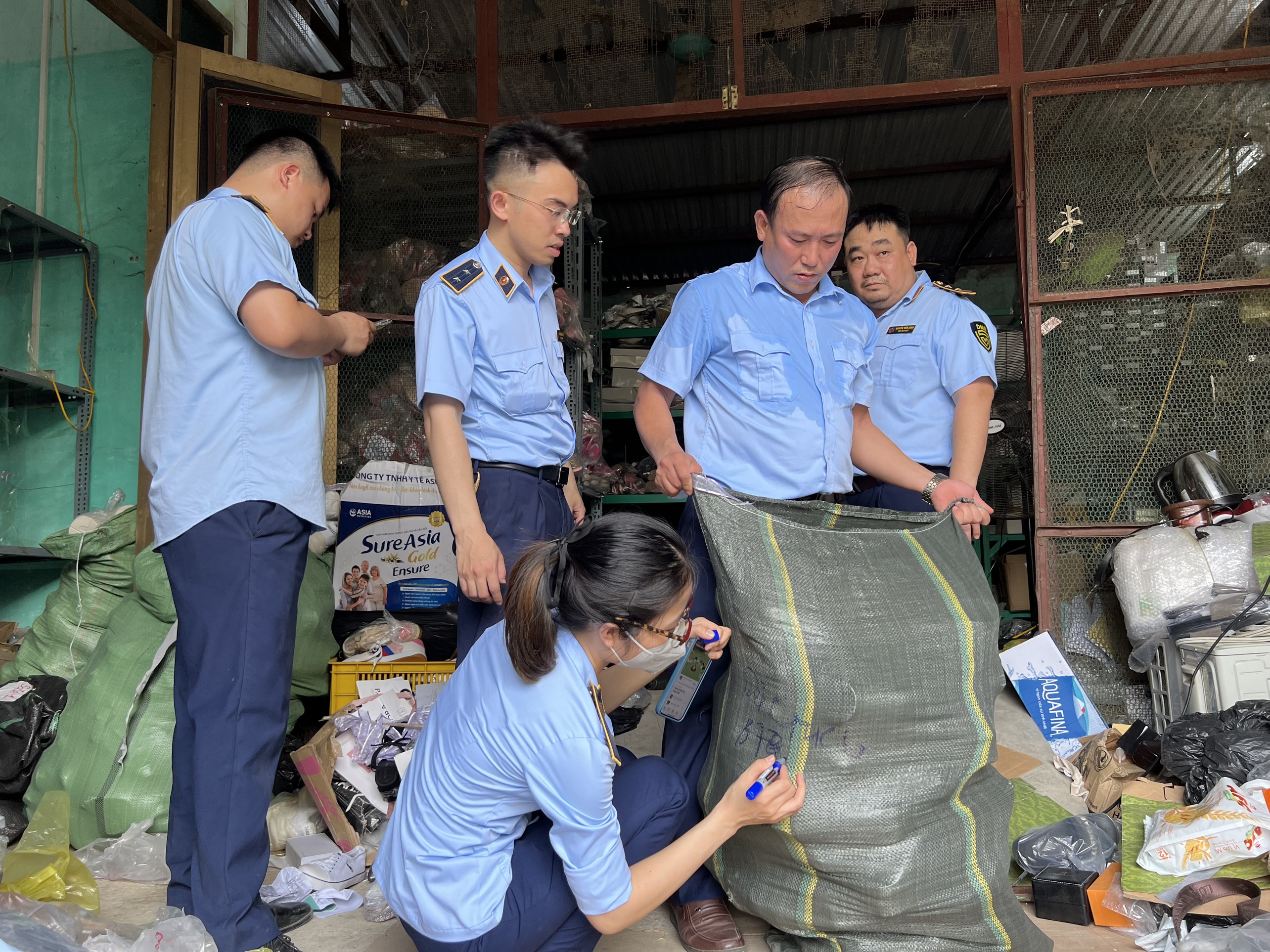 Lực lượng chức năng kiểm đếm hàng hóa nghi là hàng giả tại cơ sở của bà Trương Thị Liên
