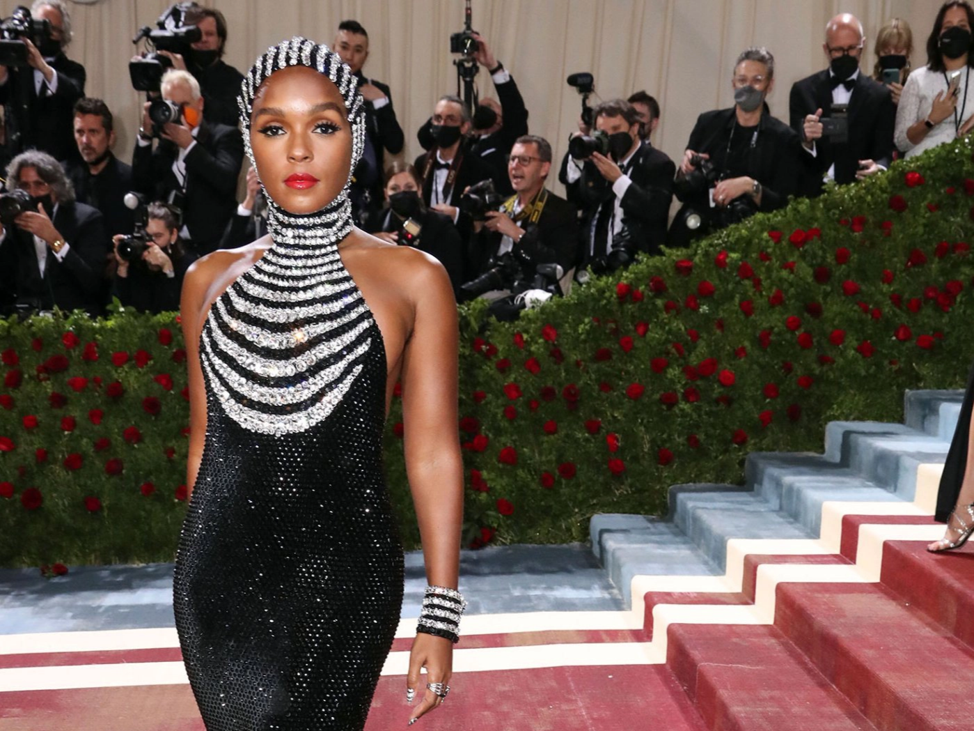 Ca sĩ Janelle Mon&aacute;e g&acirc;y ấn tượng với chiếc v&aacute;y liền mũ tr&ugrave;m đầu lạ mắt lấy cảm hứng từ thời trang hoa mỹ của thập ni&ecirc;n 50, được s&aacute;ng tạo bởi thương hiệu Ralph Lauren. Những sọc đ&aacute; qu&yacute; trắng tr&ecirc;n nền đen lấp l&aacute;nh l&agrave;m nổi bật khu&ocirc;n mặt được trang điểm theo lối ho&agrave;i cổ của nữ ca sỹ da m&agrave;u.