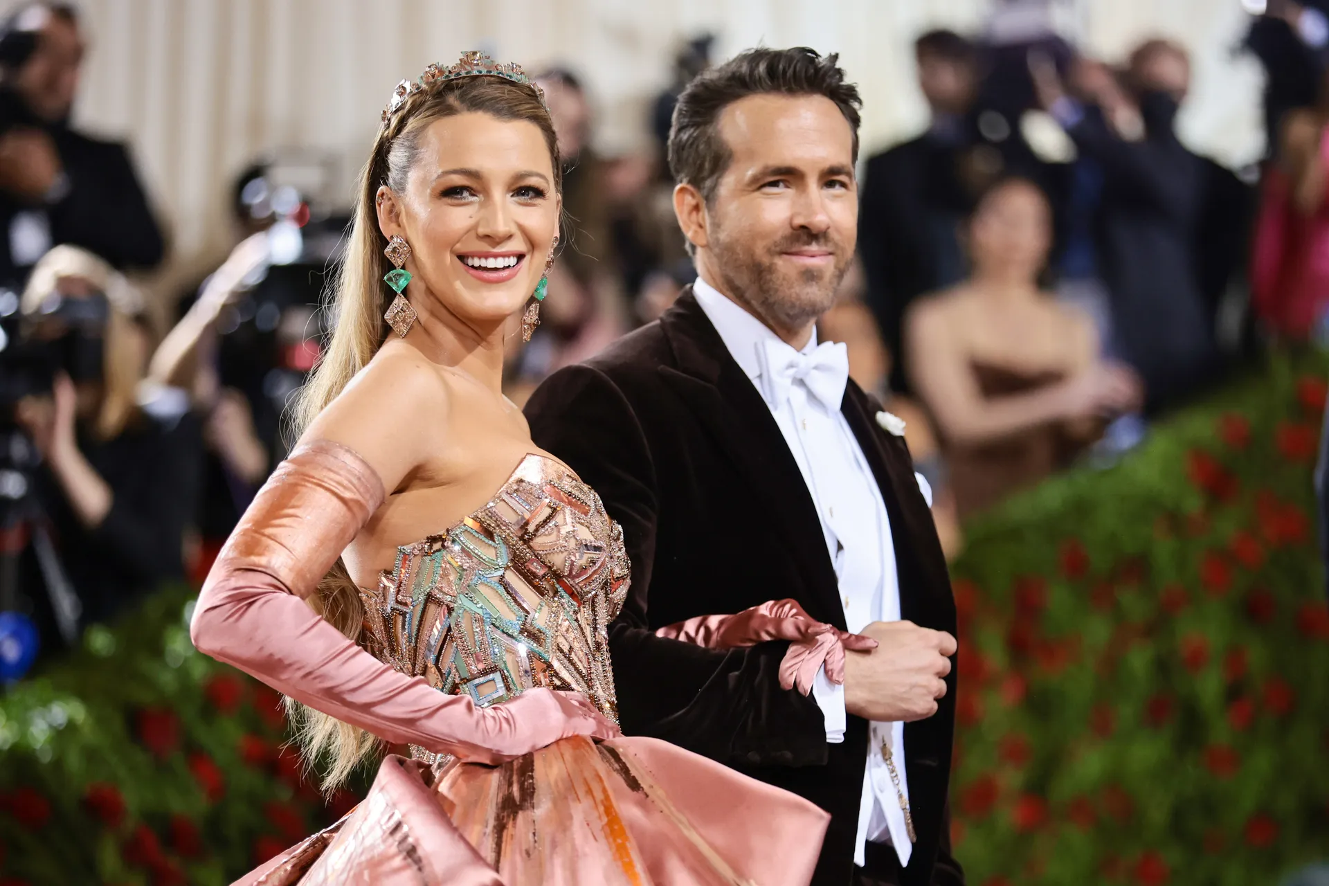 Vợ chồng Blake Lively and Ryan Reynolds giữ vai trò đồng chủ trì của sự kiện năm nay. Tài tử Deadpool xuất hiện với suit đính nơ, tuy đơn giản nhưng sang trọng. Trong khi đó, Blake khoe sắc trong thiết kế đầm chuyển màu ảo diệu từ nhà mốt Versace. Bộ cánh của Blake Lively bao gồm phần thân váy đính kết trang trọng, họa tiết thu hút đi với phần tùng váy lộng lẫy. 