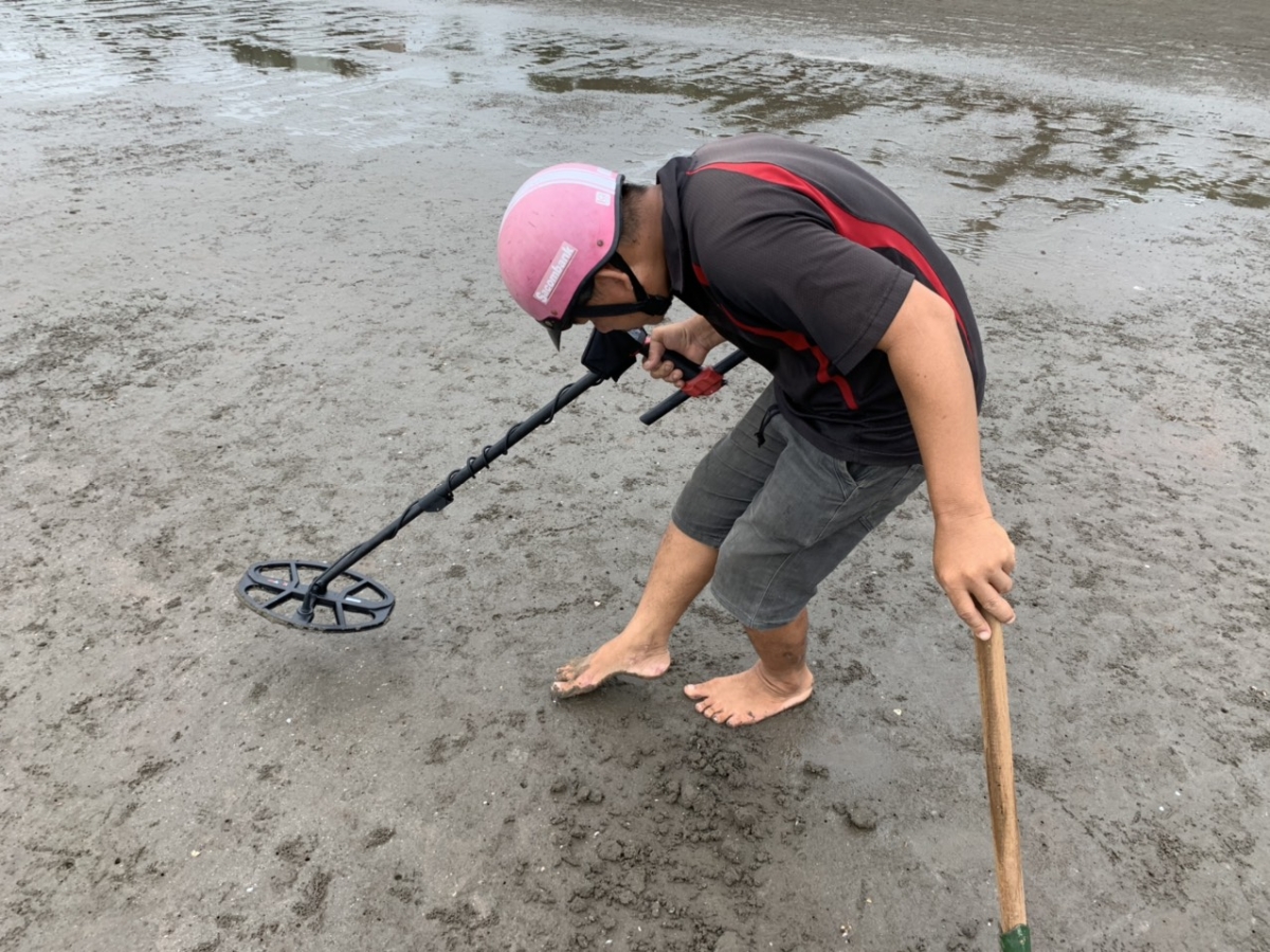 Dùng máy dò kim loại để dò tìm vòng vàng, xuyến bạc du khách đánh rơi chỉ là một trong số những công việc mưu sinh khó nhọc ven bờ biển