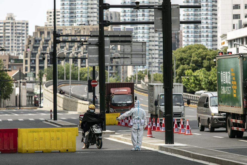 Cảnh s&aacute;t chặn một nh&acirc;n vi&ecirc;n giao h&agrave;ng đi xe m&aacute;y tại một trạm kiểm dịch tại Thượng Hải n&agrave;y 18/5 - Ảnh: Bloomberg