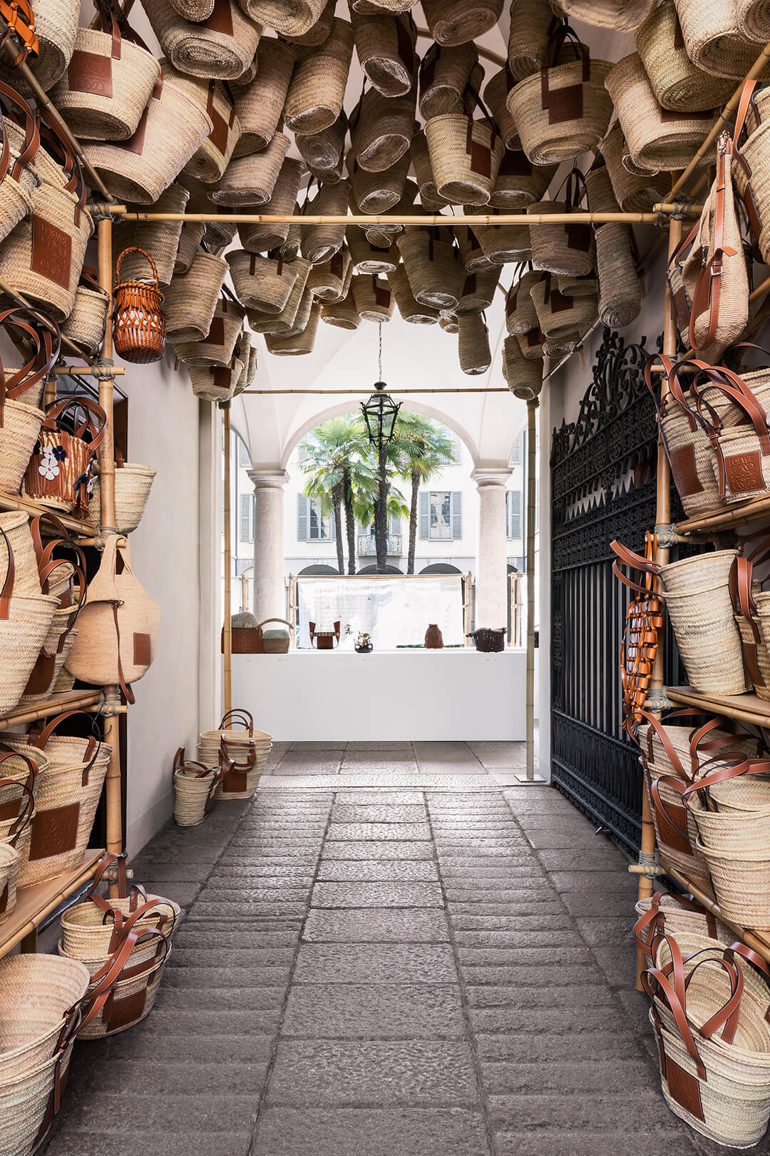 Cổng vào bằng tre uốn cong với đầy những chiếc túi cói của gian trưng bày Loewe tại Milan Design Week 2022.