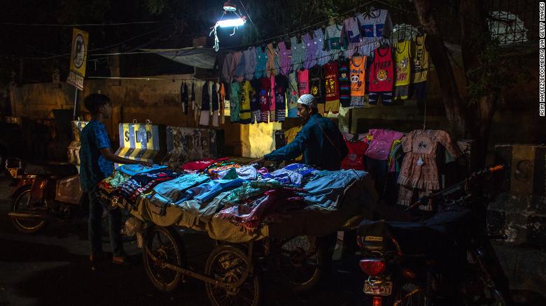 Một người bán vải dưới bóng đèn được nối với xe máy do mất điện ở Karachi, Pakistan ngày 8/6 - Ảnh: Getty Images