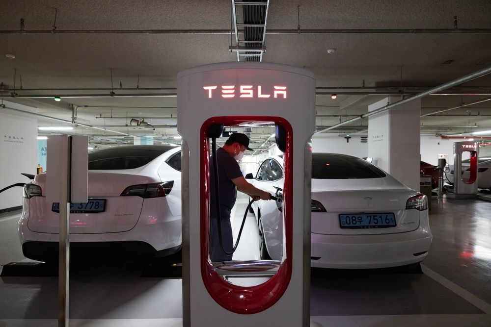 Một t&agrave;i xế sạc xe điện Tesla Model 3tại một trạm sạc ở Suwon, H&agrave;n Quốc - Ảnh: Bloomberg