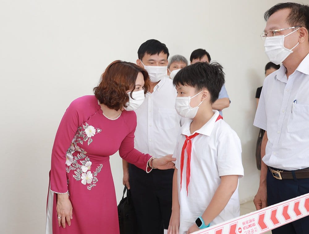 Thứ trưởng Bộ Y tế Nguyễn Thị Liên Hương động viên các em học sinh tham gia tiêm chủng. Ảnh - Hằng Phạm. 
