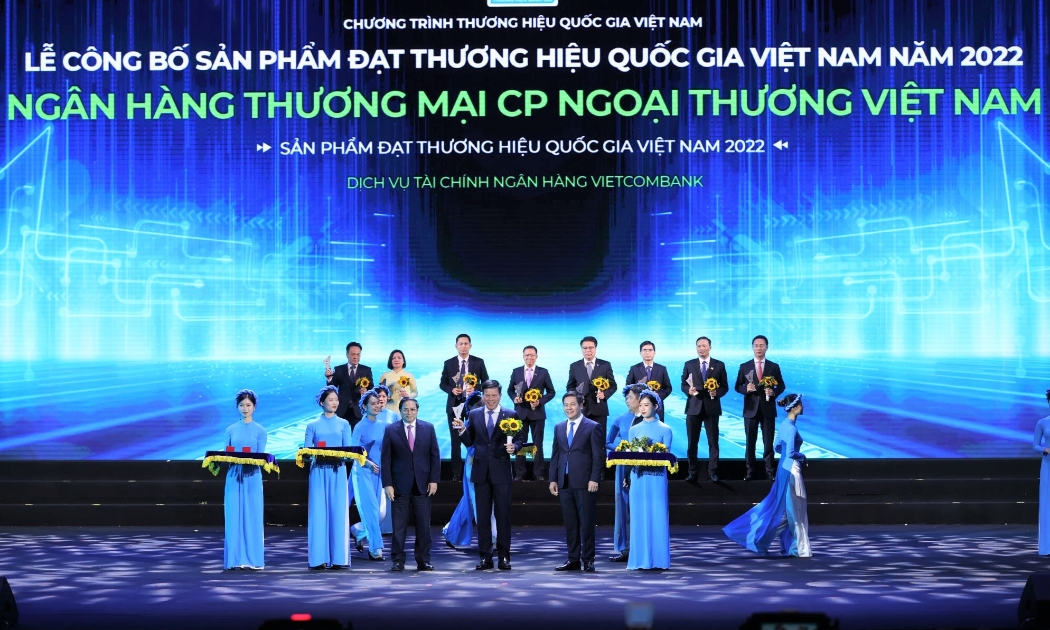 Thủ tướng Chính phủ Phạm Minh Chính (hàng đầu thứ 3 từ trái sang) trao Biểu trưng và đồng chí Nguyễn Hồng Diên - Bộ trưởng Bộ Công thương, Chủ tịch Hội đồng Thương hiệu quốc gia Việt Nam (hàng đầu thứ 2 từ phải sang) tặng hoa cho đ/c Phạm Mạnh Thắng - Phó Tổng giám đốc Vietcombank.