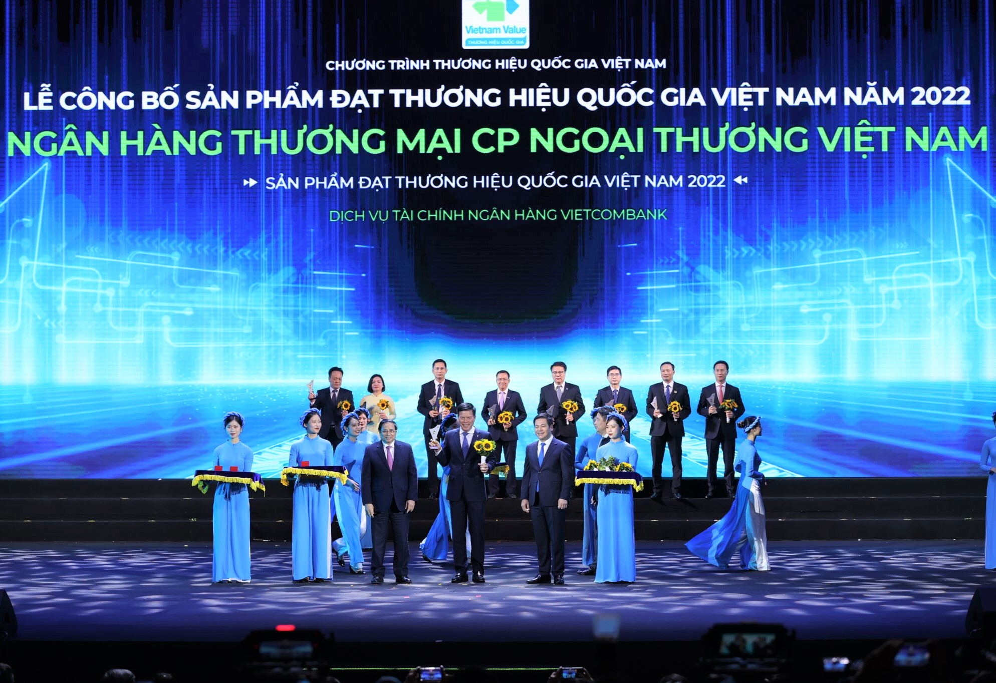 Thủ tướng Chính phủ Phạm Minh Chính (hàng đầu thứ 3 từ trái sang) trao Biểu trưng và đồng chí Nguyễn Hồng Diên - Bộ trưởng Bộ Công thương, Chủ tịch Hội đồng Thương hiệu quốc gia Việt Nam (hàng đầu thứ 2 từ phải sang) tặng hoa cho đ/c Phạm Mạnh Thắng - Phó Tổng giám đốc Vietcombank.