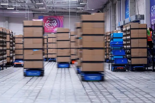 Robot tự động (bệ màu xanh dương phía dưới) di chuyển sản phẩm trong một nhà kho ở Cainiao, Trung Quốc.