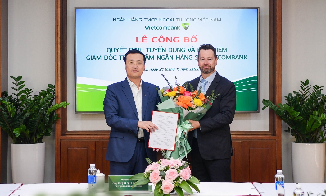 Ông Phạm Quang Dũng - UV BTV Đảng ủy Khối DNTW, Bí thư Đảng ủy, Chủ tịch HĐQT Vietcombank (bên trái) trao quyết định và tặng hoa chúc mừng tân Giám đốc Trung tâm ngân hàng số Vietcombank.