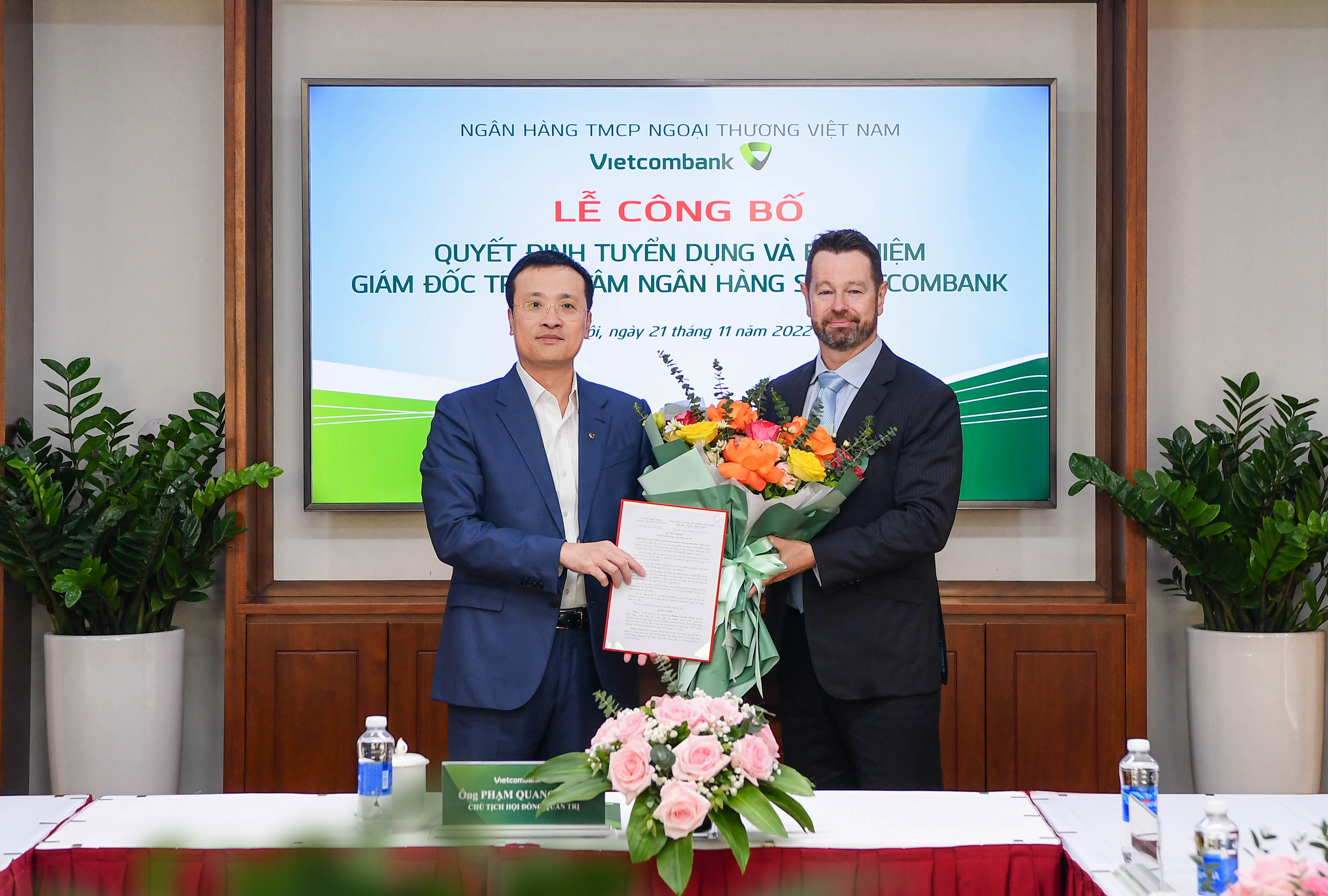 Ông Phạm Quang Dũng - UV BTV Đảng ủy Khối DNTW, Bí thư Đảng ủy, Chủ tịch HĐQT Vietcombank (bên trái) trao quyết định và tặng hoa chúc mừng tân Giám đốc Trung tâm ngân hàng số Vietcombank.