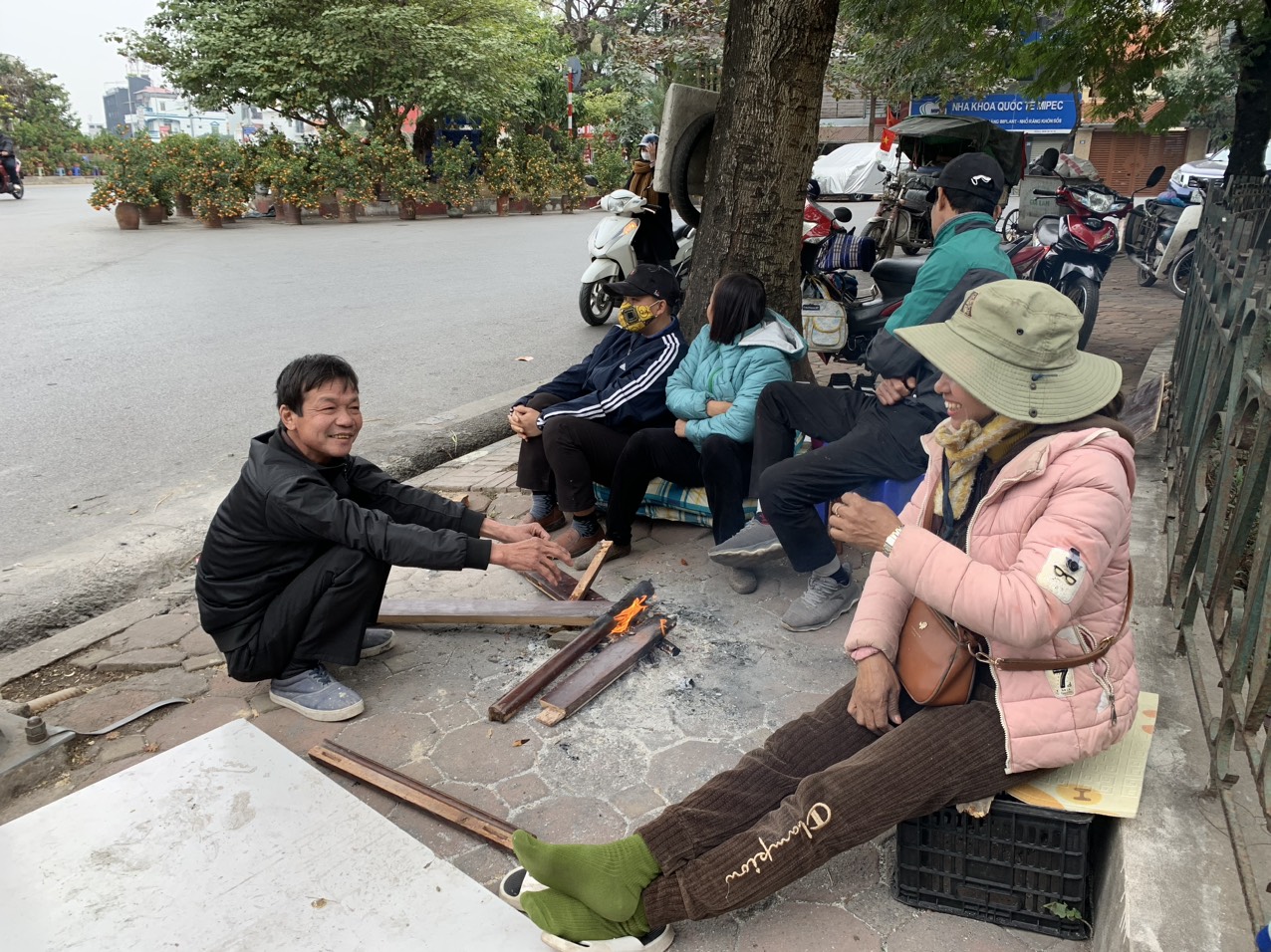 Chiều 26 Tết, do vắng kh&aacute;ch n&ecirc;n nh&oacute;m những người bu&ocirc;n đ&agrave;o, quất tụ tập với nhau đốt lửa để sưởi ấm. Chị Ho&agrave;ng Thị Lan chia sẻ, hy vọng người d&acirc;n sẽ đi mua đ&agrave;o quất sớm, nếu đến chiều 30 Tết m&agrave; vẫn c&ograve;n tồn nhiều h&agrave;ng th&igrave; đ&agrave;nh b&aacute;n rẻ bằng 1/2 thậm ch&iacute; bằng 1/3 gi&aacute; hiện nay.&nbsp;