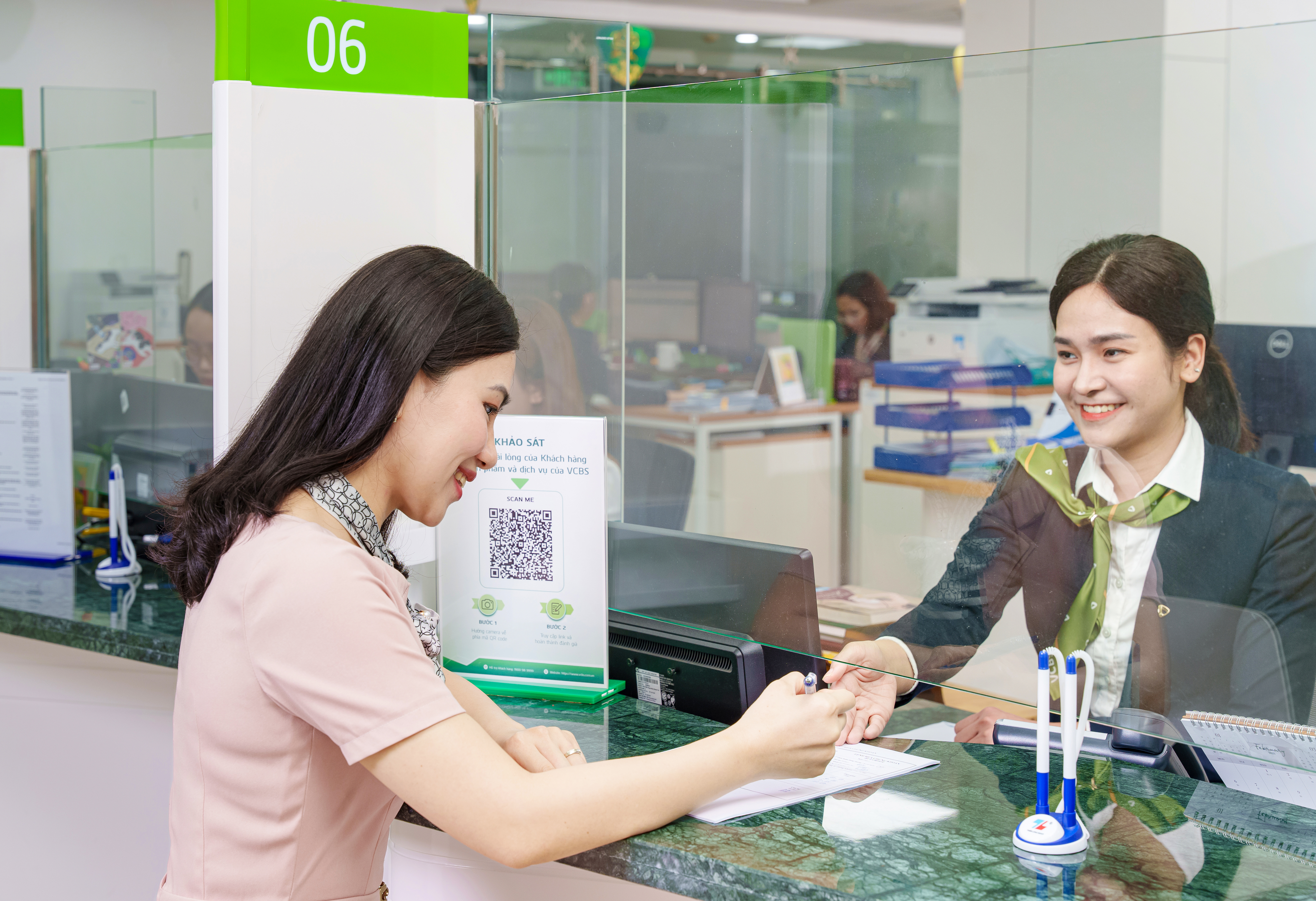 Tư vấn viên hướng dẫn khách hàng làm thủ tục hồ sơ tại Phòng Giao dịch VCBS.