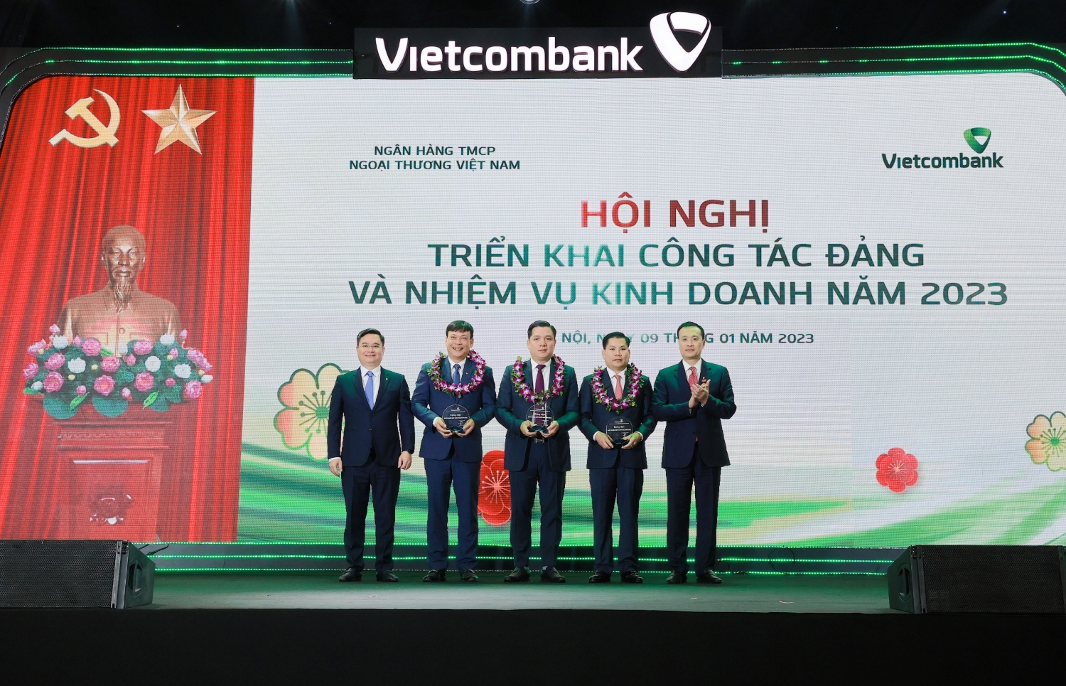 Đồng chí Phạm Quang Dũng - Ủy viên Ban Thường vụ Đảng ủy Khối DNTW, Bí Thư Đảng ủy, Chủ tịch HĐQT Vietcombank (ngoài cùng bên phải) và đồng chí Nguyễn Thanh Tùng - Phó Tổng Giám đốc phụ trách Ban điều hành (ngoài cùng bên trái) trao biểu trưng và tặng hoa cho 3 chi nhánh xuất sắc nhất hệ thống năm 2022 tại Hội nghị triển khai công tác Đảng và nhiệm vụ kinh doanh năm 2023 diễn ra tại Hà Nội, ngày 9/1/2023.