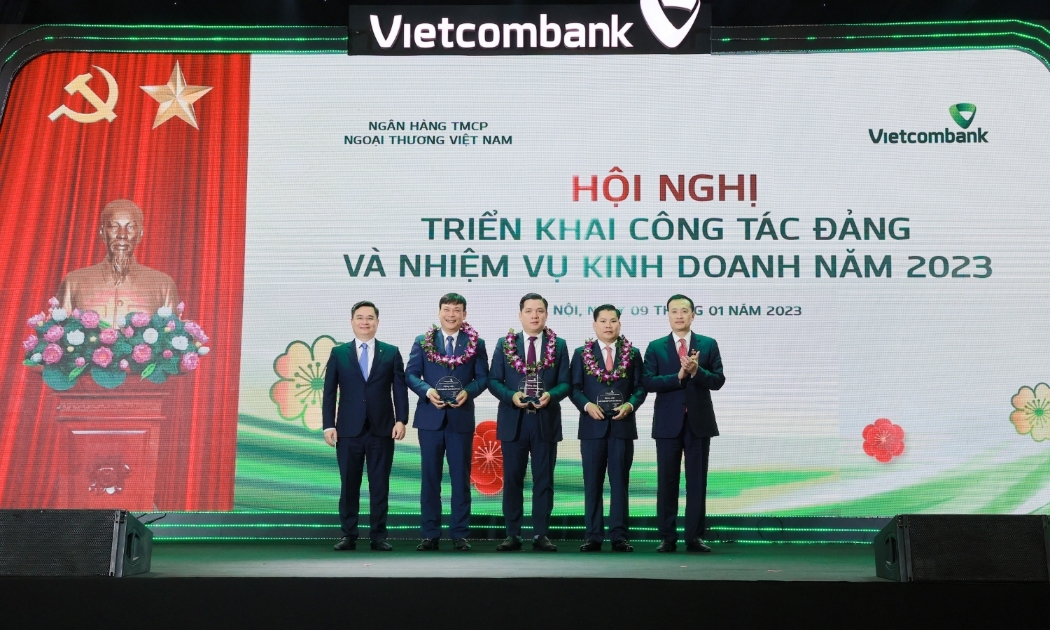 Đồng chí Phạm Quang Dũng - Ủy viên Ban Thường vụ Đảng ủy Khối DNTW, Bí Thư Đảng ủy, Chủ tịch HĐQT Vietcombank (ngoài cùng bên phải) và đồng chí Nguyễn Thanh Tùng - Phó Tổng Giám đốc phụ trách Ban điều hành (ngoài cùng bên trái) trao biểu trưng và tặng hoa cho 3 chi nhánh xuất sắc nhất hệ thống năm 2022 tại Hội nghị triển khai công tác Đảng và nhiệm vụ kinh doanh năm 2023 diễn ra tại Hà Nội, ngày 9/1/2023.