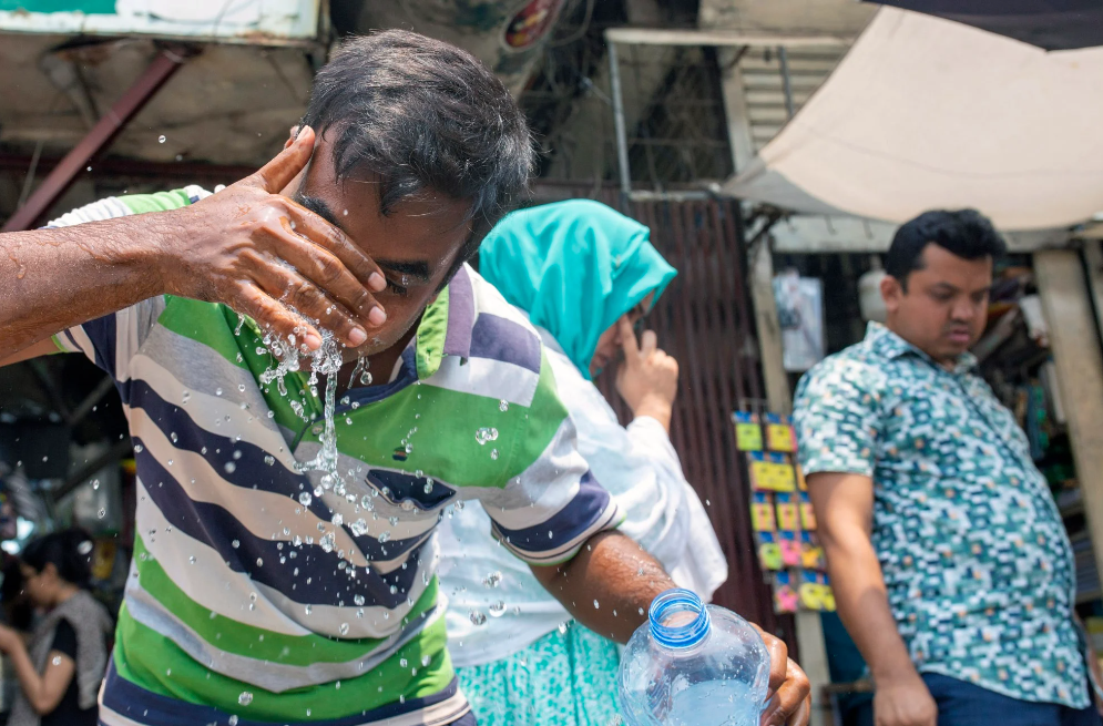 Một người đàn ông té nước lên mặt để giải nhiệt ở Dhaka, Bangladesh. Nhiều con đường tại nước này đã chảy nhựa vì nắng nóng gay gắt trong tháng trước - Ảnh: EPA-EFE