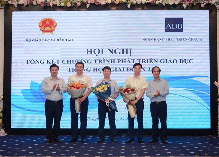 Bộ trưởng Nguyễn Kim Sơn và Thứ trưởng Nguyễn Hữu Độ tặng hoa chúc mừng Ban Quản lý Chương trình. Ảnh: Bộ Giáo dục và Đào tạo.