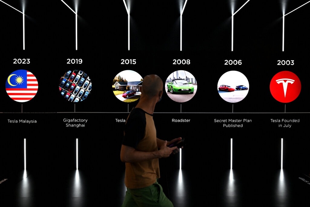 Một người đ&agrave;n &ocirc;ng đi qua c&aacute;c biểu ngữ của Tesla trong buổi ra mắt c&ocirc;ng ty &ocirc; t&ocirc; lần đầu ti&ecirc;n tại Kuala Lumpur. Ảnh: Mohd RASFAN/AFP