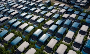 Nằm trong cỏ dại và rác rưởi, hàng trăm chiếc xe điện bị vứt bỏ. Ảnh: Qilai Shen/Bloomberg