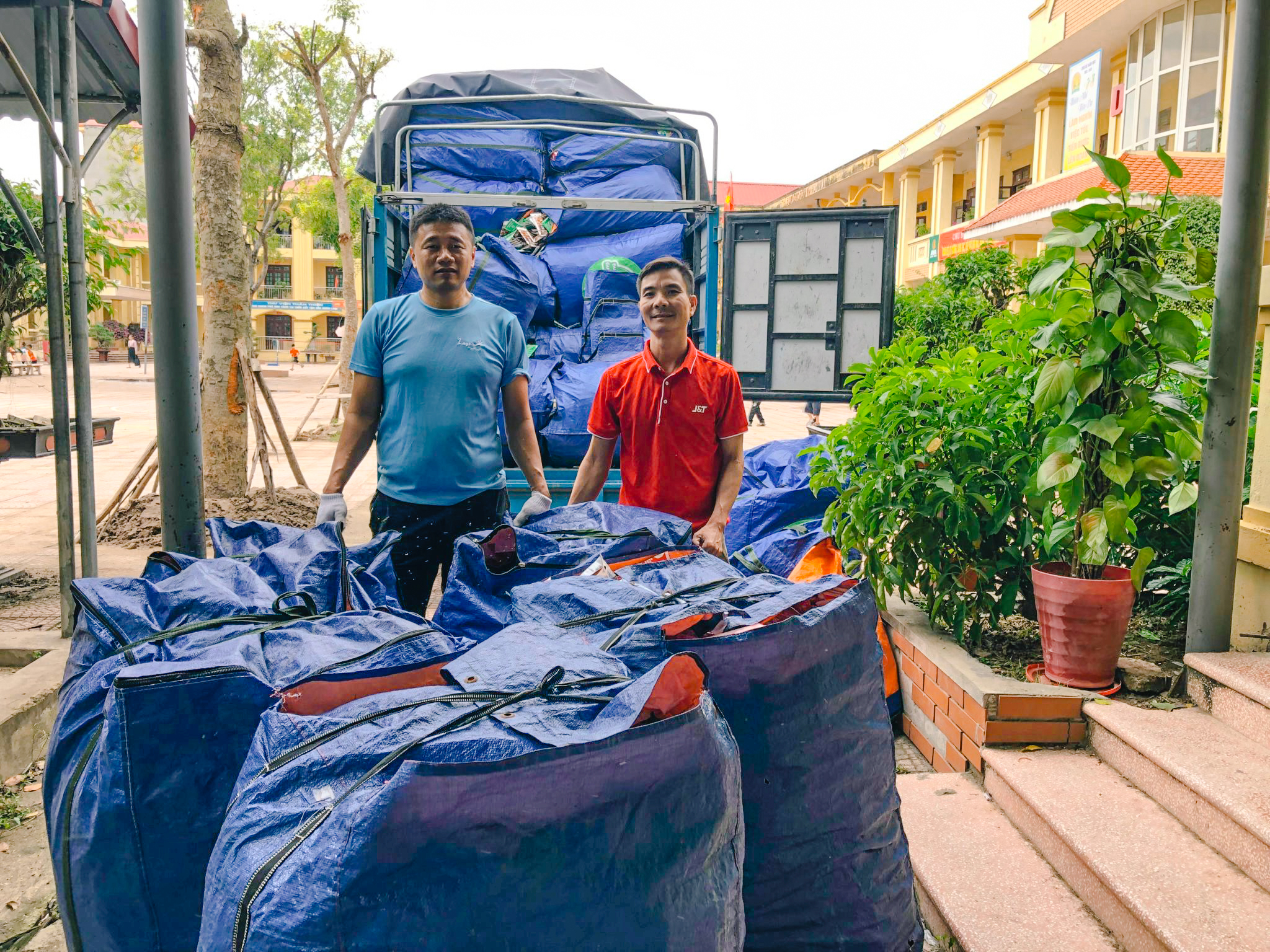 Nh&acirc;n vi&ecirc;n J&T Express v&agrave; chị Loan - đại diện Điểm tập kết số 13 ph&acirc;n loại r&aacute;c thải nhựa th&agrave;nh từng bao trước khi chuyển đi t&aacute;i chế.