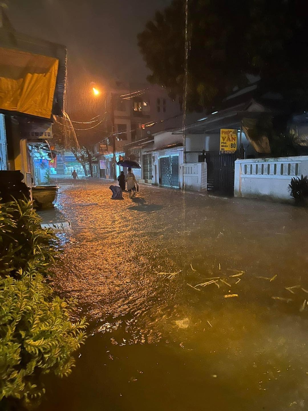Một người d&acirc;n th&agrave;nh phố Huế b&igrave; b&otilde;m lội bộ trong d&ograve;ng nước lũ để trở về nh&agrave;