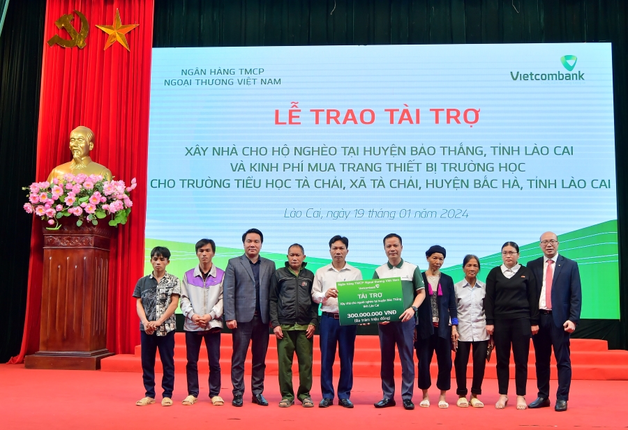 &Ocirc;ng L&ecirc; Ho&agrave;ng T&ugrave;ng - Ph&oacute; Tổng Gi&aacute;m đốc Vietcombank (thứ 5 từ phải sang) c&ugrave;ng &ocirc;ng Đặng Việt H&ugrave;ng &ndash; B&iacute; thư Chi bộ, Gi&aacute;m đốc Vietcombank L&agrave;o Cai (ngo&agrave;i c&ugrave;ng b&ecirc;n phải) trao biểu trưng số tiền 300 triệu đồng cho 6 hộ gia đ&igrave;nh kh&oacute; khăn tại huyện Bảo Thắng.