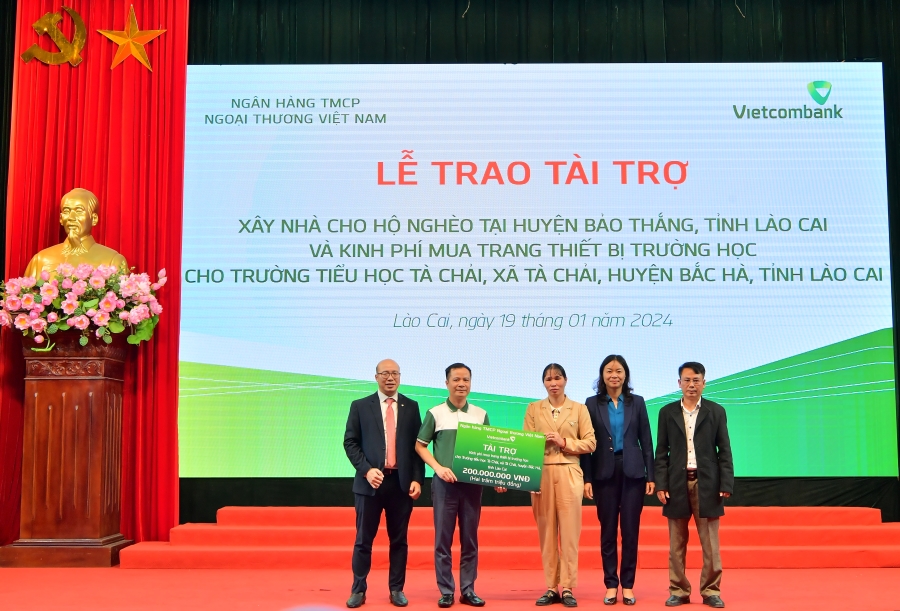 &Ocirc;ng L&ecirc; Ho&agrave;ng T&ugrave;ng - Ph&oacute; Tổng Gi&aacute;m đốc Vietcombank (thứ 2 từ tr&aacute;i sang) c&ugrave;ng &ocirc;ng Đặng Việt H&ugrave;ng &ndash; B&iacute; thư Chi bộ, Gi&aacute;m đốc Vietcombank L&agrave;o Cai (ngo&agrave;i c&ugrave;ng b&ecirc;n tr&aacute;i) trao biểu trưng t&agrave;i trợ 200 triệu đồng kinh ph&iacute; mua trang thiết bị trường học cho Trường tiểu học T&agrave; Chải, x&atilde; T&agrave; Chải, huyện Bắc H&agrave;, tỉnh L&agrave;o Cai.
